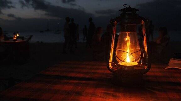 浪漫的烛光晚餐在海洋海滩晚上煤油灯在桌子上点燃