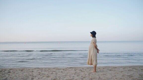 亚洲孕妇走在沙滩上