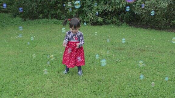 小女孩在春天的花园里玩泡泡