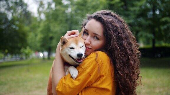 善良的女士抱着狗在公园亲吻和拥抱宠物在夏天的肖像