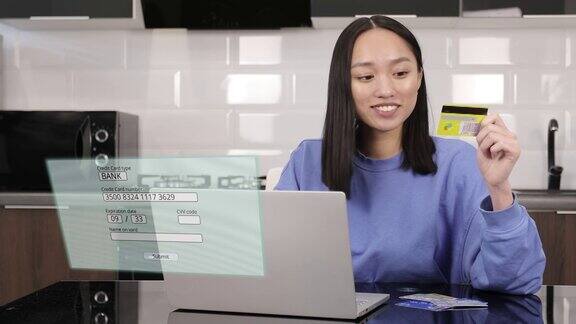 年轻的亚洲女性持卡人手中持有信用卡进行网上银行支付