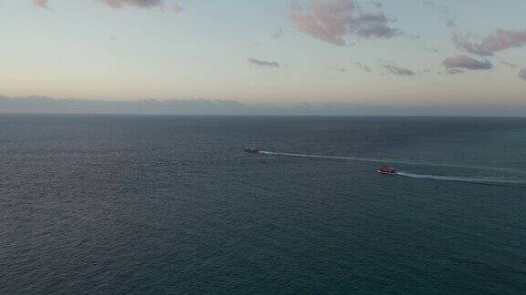 航拍镜头跟随两艘船出海在日出-侧视图