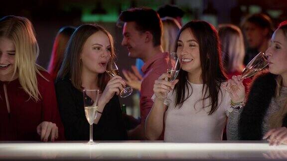 四个迷人的女孩在俱乐部的酒吧举起他们的香槟杯