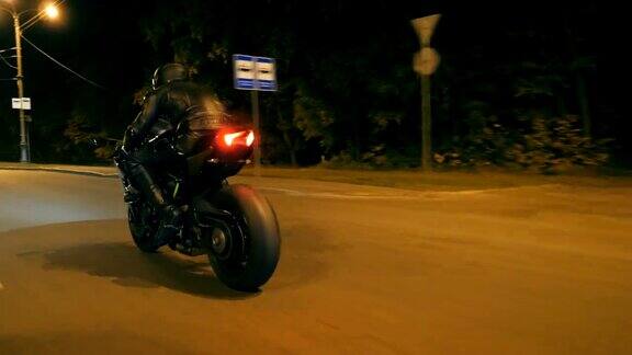 一个骑摩托车的人在夜间的公路上比赛一个戴着头盔的年轻人在夜晚的街道上骑着现代摩托车飞驰一个家伙在黄昏时分骑着自行车自由和冒险侧视图