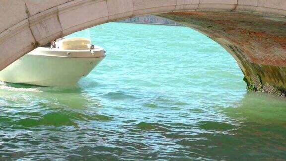 一艘白色快艇从小桥底下驶过