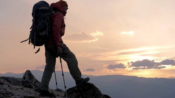 背着背包的剪影游客在日落时分在山顶欣赏风景