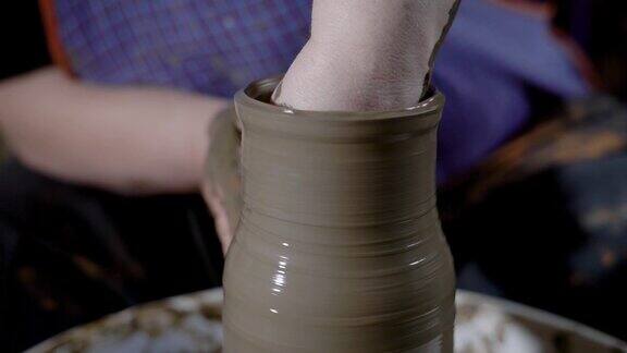 这是陶土花瓶的特写镜头材料在双手的帮助下形成产品的形状罐子站在陶工的转盘上