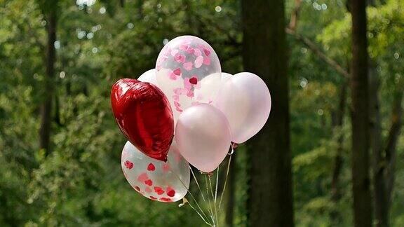 很多粉色的氦气球和一个大的红色心形气球