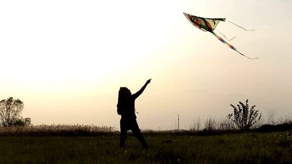 日落时分可爱的小女孩在草地上放风筝