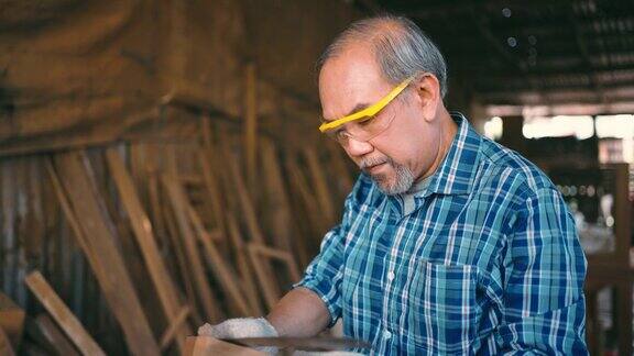 活跃的老木匠在闲暇时间与木材一起工作