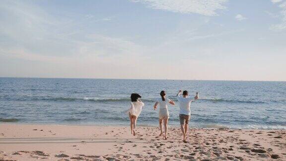 一群快乐的亚洲年轻朋友在暑假里一起在海滩上奔跑和跳跃