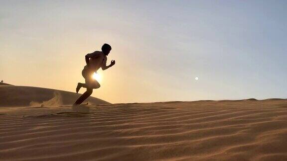 一个男人跑上沙漠中的沙丘的慢镜头