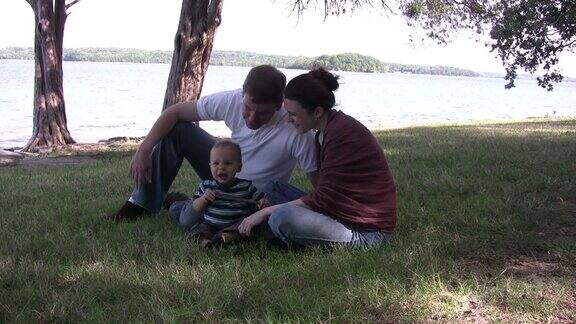 一个年轻的家庭坐在HD湖边