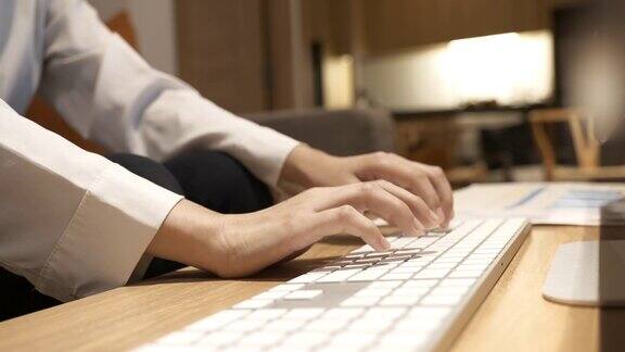亚洲妇女在家里工作时用手敲击键盘的场景