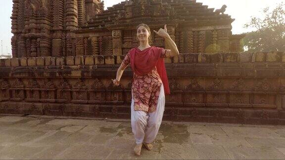 年轻的印度妇女在古庙前跳传统的奥迪西舞
