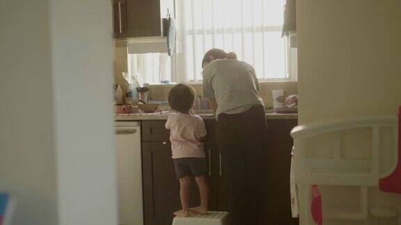 年轻的母亲和儿子在厨房的水槽洗手