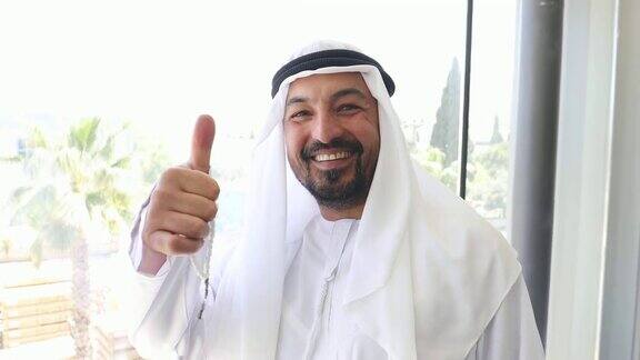 自信的阿拉伯商人在办公室里竖起大拇指的肖像