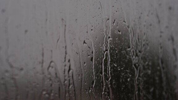 小雨打在窗口水滴和溪水从玻璃杯里流下来