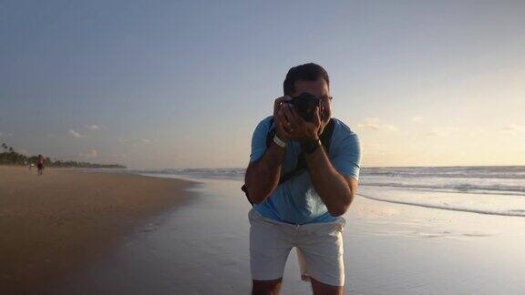 摄影师在日出时在海滩上拍照