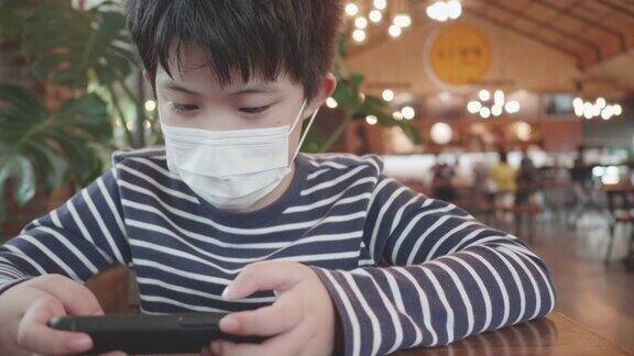 戴着面具玩手机游戏的亚洲男孩