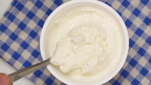 用勺子舀出新鲜的酸奶放在桌子上的碗里