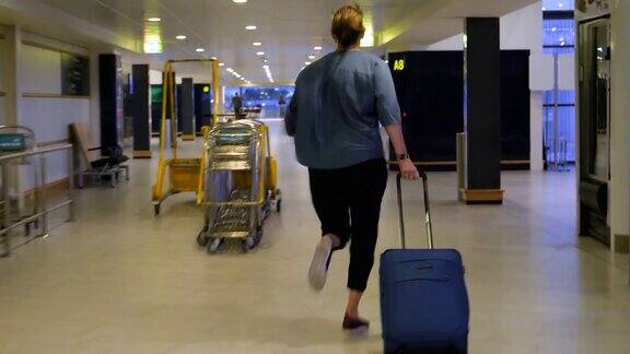 压力山大的女人提着行李箱在机场跑到登机口