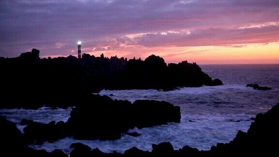 黄昏时强大的灯塔和岩石嶙峋的海岸线