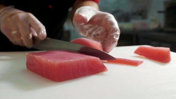 特写寿司厨师在手套切片新鲜的红鱼片在寿司吧