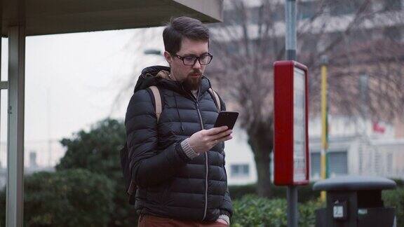 市民手持智能手机在车站等公交车