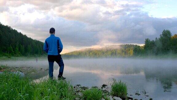 男人站在晨雾缭绕的透明湖畔