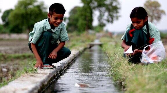 学校的孩子们在水渠附近玩纸船