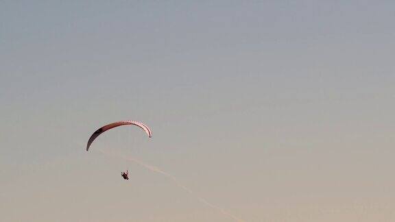 独自滑翔伞在日落时在清澈的彩色天空中飞得很高在阳光明媚的日子里在空中滑翔极限运动