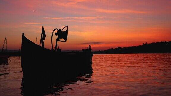 古老的木制渔船剪影锚在码头对戏剧性的日落天空