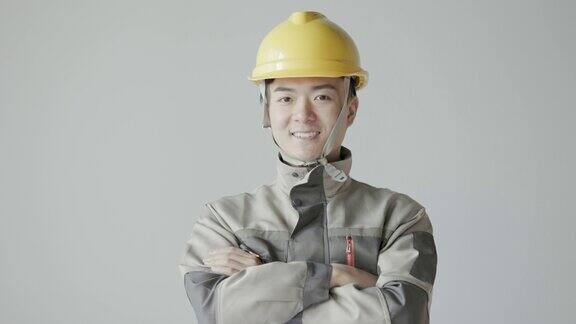 年轻的亚洲男工程师戴着头盔穿着工作服对着镜头微笑中国工人和工程师