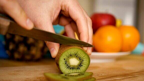 男子用刀在木板上切猕猴桃背景是水果和蔬菜特写镜头