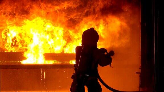 4K消防队员使用消防水龙带扑灭正在燃烧的建筑物内的火灾