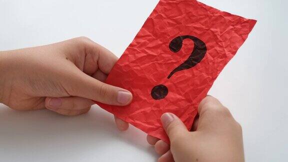 一个孩子拿着一张满是皱纹的红色纸条上面有一个问号