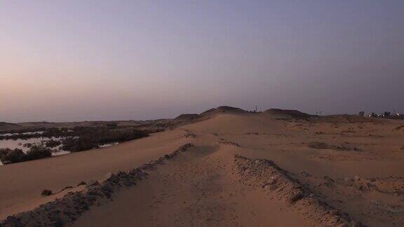 在日落时分走在沙丘上摄像机沿着沙漠中的大沙丘移动