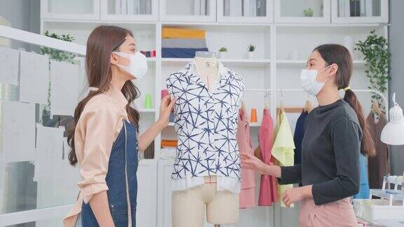 亚洲美丽的裁缝女人工作在裁缝工作室的衣服迷人的年轻女孩时装设计师用卷尺测量新的手工制作的服装在车间的人体模型时尚的经营理念