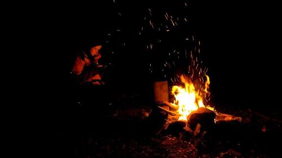 晚上在森林的篝火旁拿着智能手机的女孩