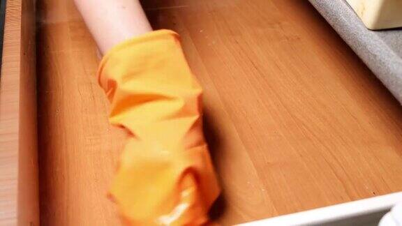 一位戴橡胶手套的妇女在清洗厨房的抽屉打扫房子