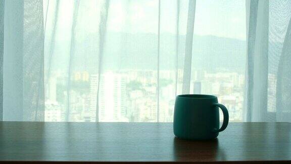 一杯咖啡放在窗帘旁边的桌子上