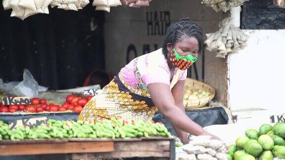 年轻妇女戴着防护口罩在非洲食品市场工作