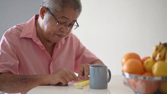 亚裔华人老人正在把药品放在药片收纳器里