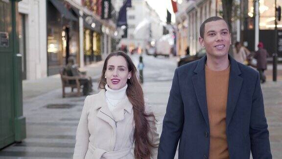 一对年轻夫妇走在城市的街道上进行圣诞购物