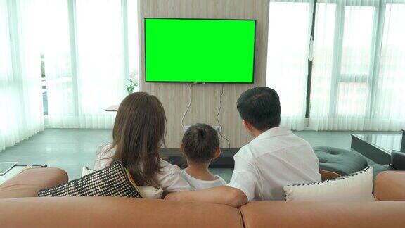 亚洲幸福家庭坐在家里的客厅看电视一起度过有质量的时间活动在假期假日幸福或生活方式
