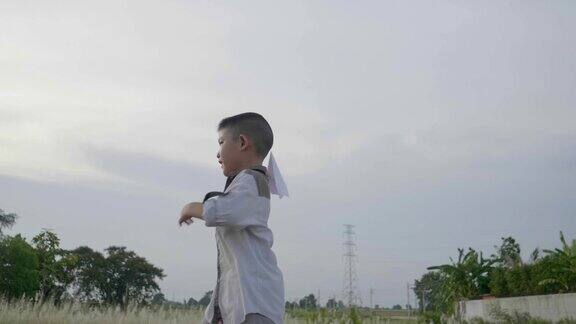 慢镜头亚洲小男孩跑着玩飞纸飞机