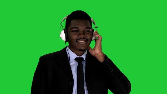英俊的非洲裔美国商人戴着耳机在绿色屏幕上听音乐ChromaKey