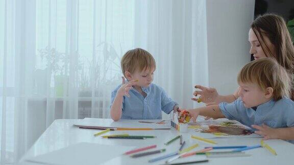 两个孩子的男孩和母亲从事创造性发展做家庭作业的手指在纸上触觉和小数学的发展
