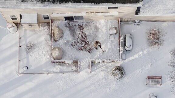 一名成年男子在一场冬季降雪后用铁铲清理门廊上的积雪鸟瞰无人机视频